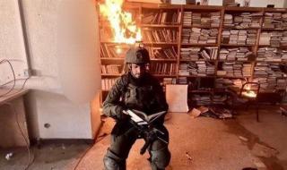 جندي يلتقط صورة مع مكتبة جامعة الأقصى بعد حرقها